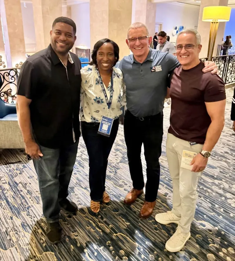 Four attendees smiling together in a hotel lobby at MIC 2026.